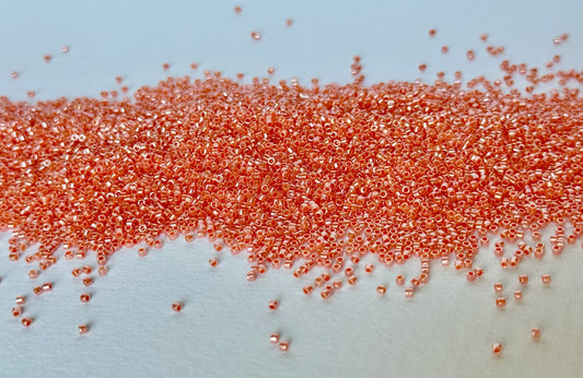 Close up of orange beads spilled on a white surface.
