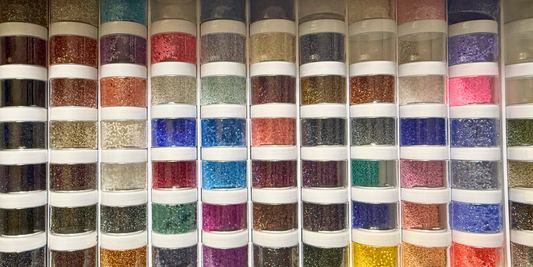 Stacked plastic jars filled with brightly coloured beads.