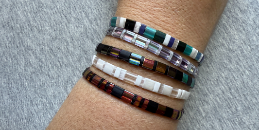 Forearm on a grey background with beaded bracelets in many colours
