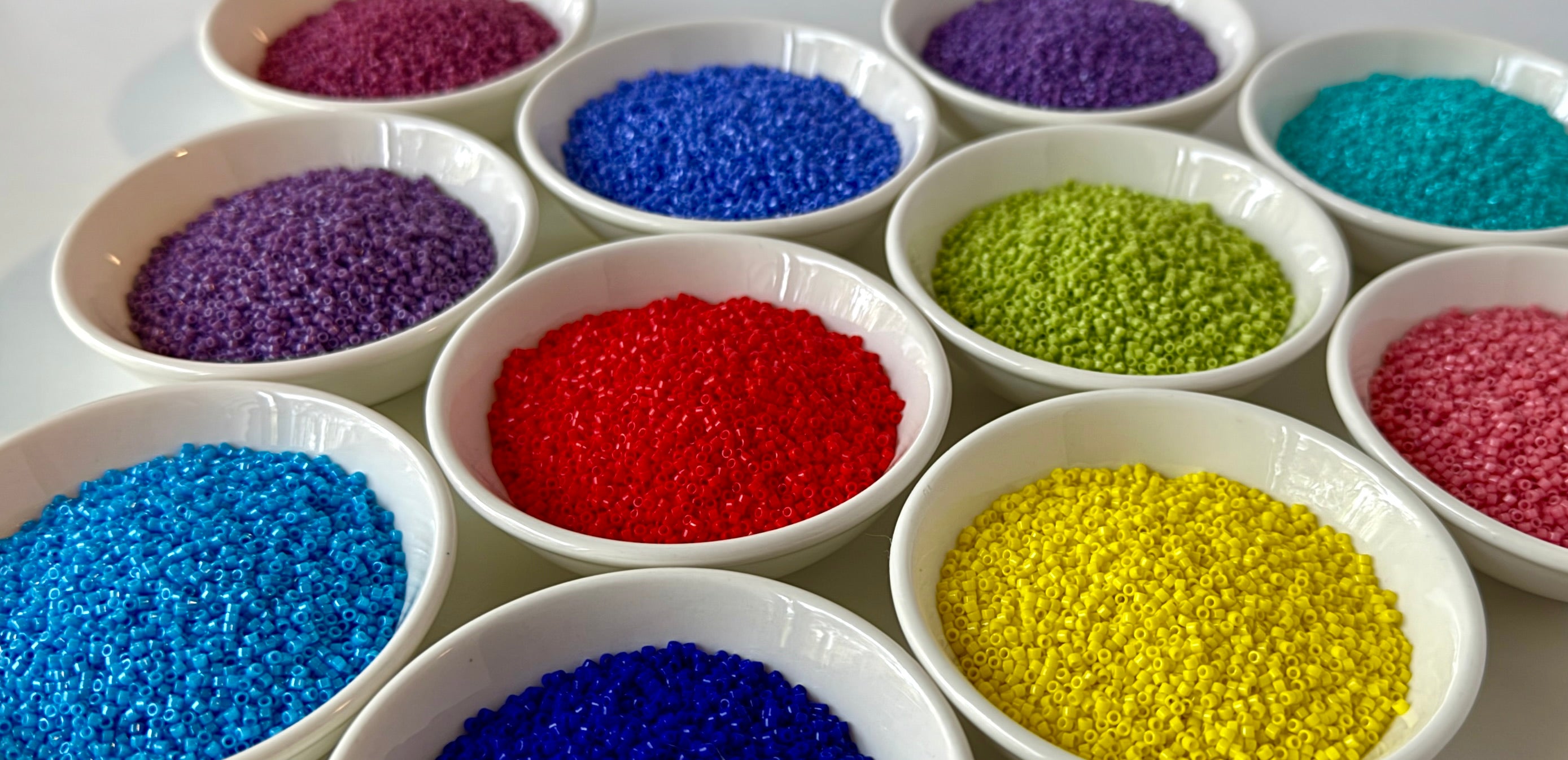 Close up of brightly coloured beads in small bowls.