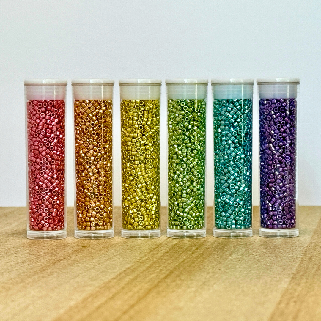 Close up of six tubes of beads in bright colours.